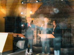 Three speakers standing behind podiums on a stage