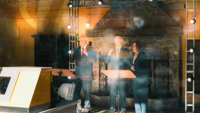 Three speakers standing behind podiums on a stage