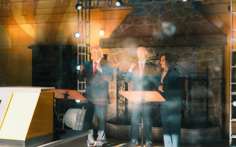 Three speakers standing behind podiums on a stage