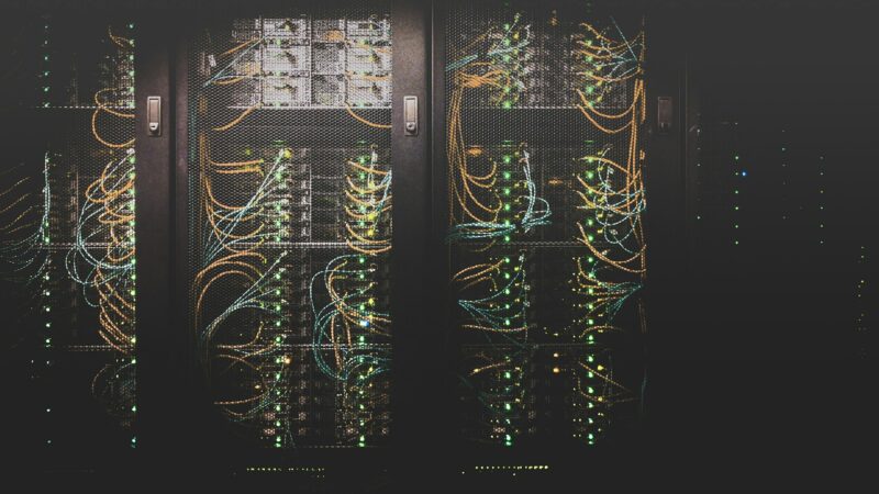 Rows of grey network cables running into server racks in a data centre