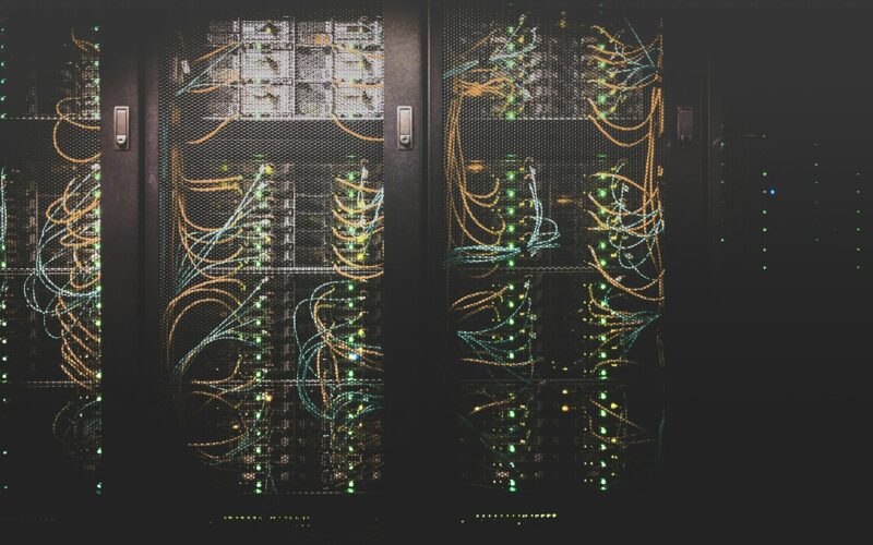 Rows of grey network cables running into server racks in a data centre
