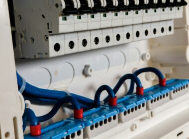 Open electrical panel showing a row of circuit breakers above blue wiring
