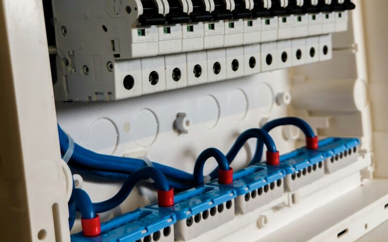 Open electrical panel showing a row of circuit breakers above blue wiring