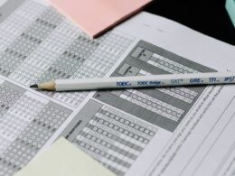 Printed spreadsheets with columns of figures and a pencil lying across them