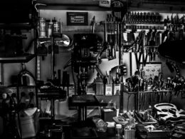 Metal hand tools arranged on a workshop wall in grayscale