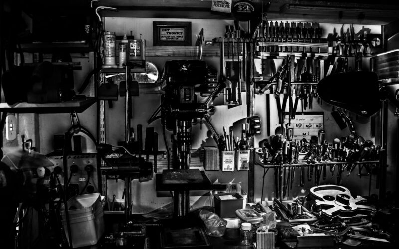 Metal hand tools arranged on a workshop wall in grayscale