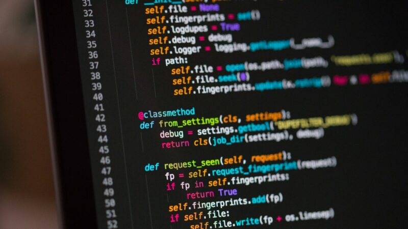Close view of a laptop screen showing lines of code in a dark editor