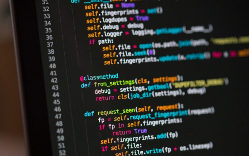 Close view of a laptop screen showing lines of code in a dark editor