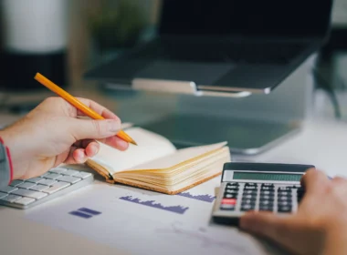 A person sitting at a desk with a calculator and a notebook