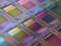 A silicon wafer with a grid of iridescent microchip dies under shallow