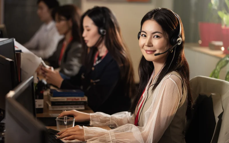 A smiling woman wearing a headset at a computer