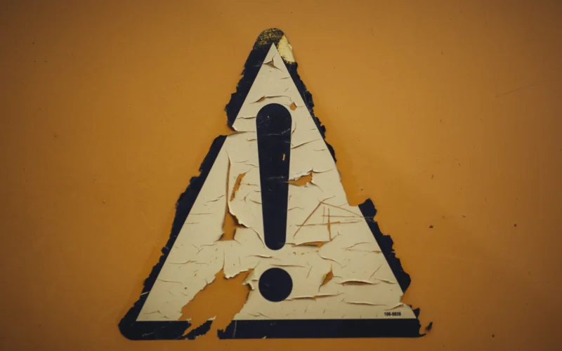 A triangle shaped sign on a yellow wall