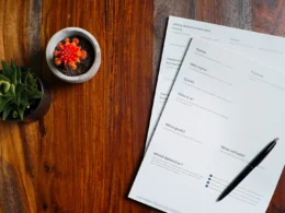 A wooden table topped with papers and a pen