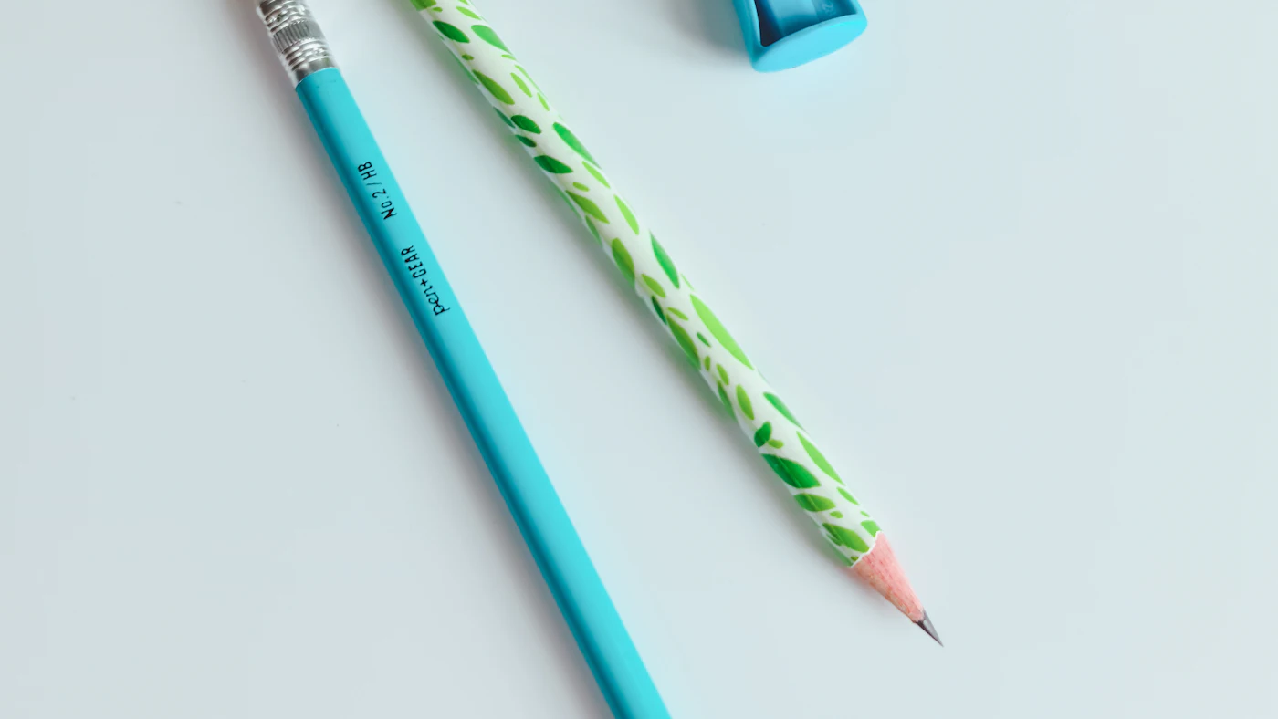 Two pencils on a pale blue surface