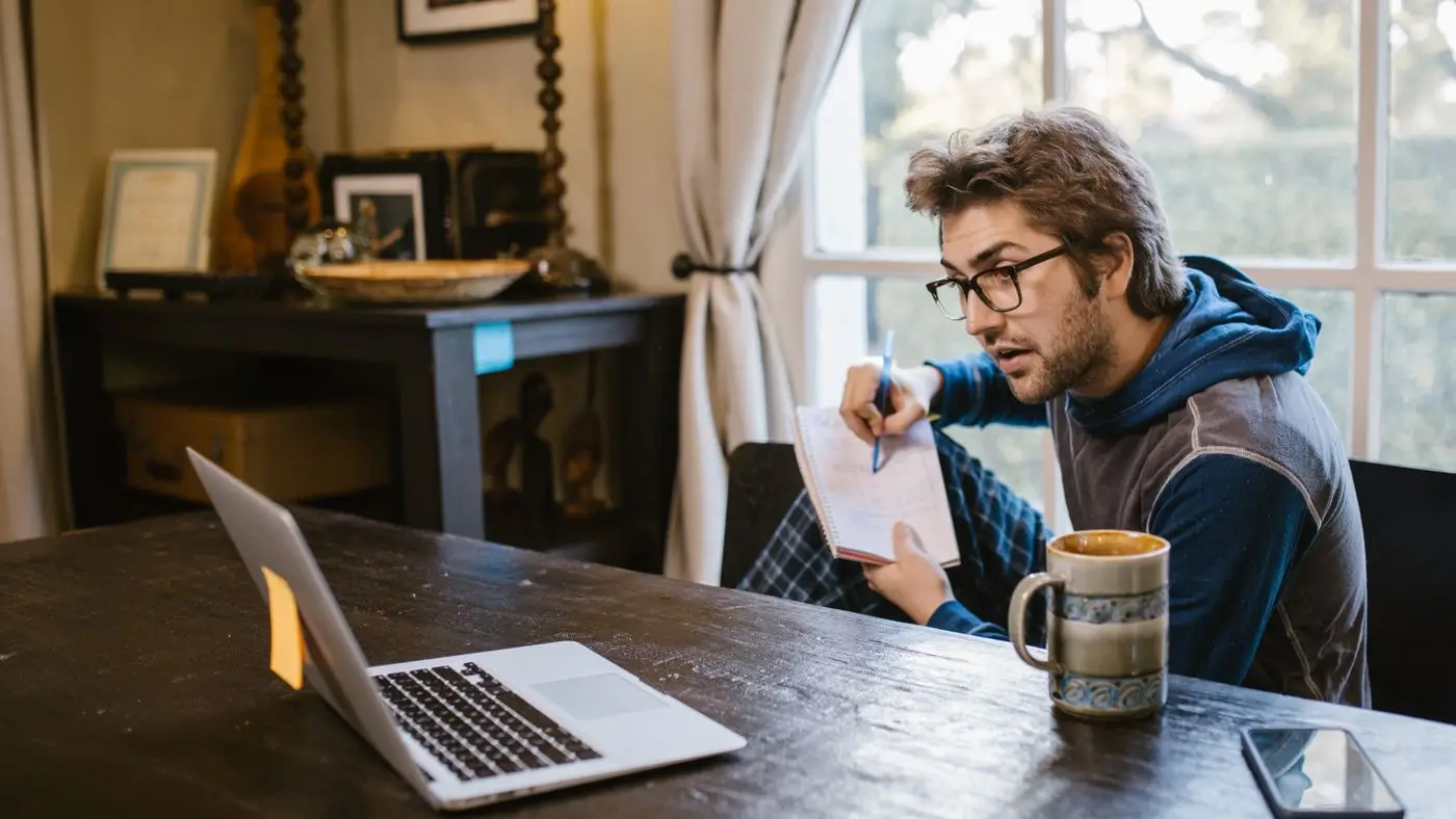 AI pace of change: man taking notes on a notepad while working on a laptop