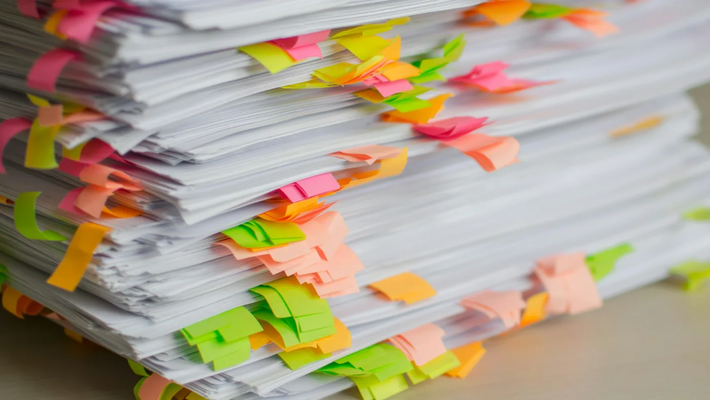 AI slop grenades: stack of papers marked with colourful sticky tabs.