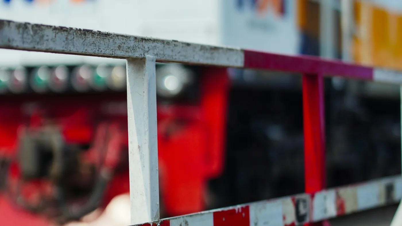 Red and white railway crossing gate lowered with a blurred train behind.