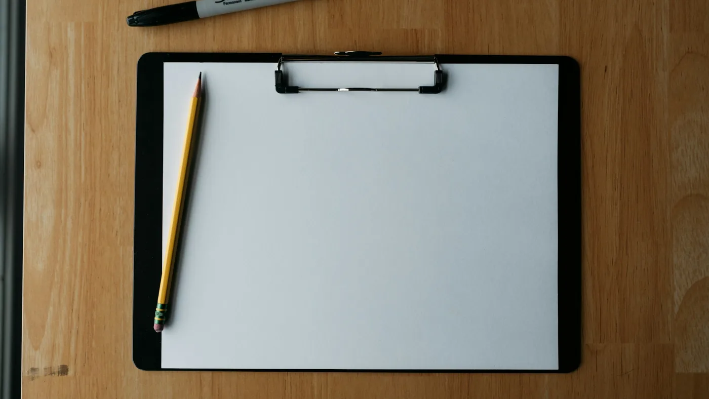 AI vendor safety risk: clipboard, pencil and pen resting on a wooden surface.