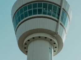 A tall white airport control tower against an open sky