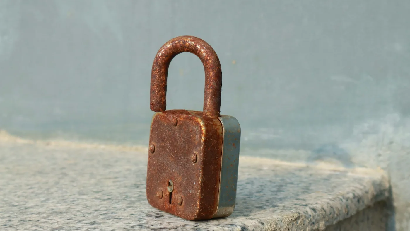 A rusty padlock on a stone ledge