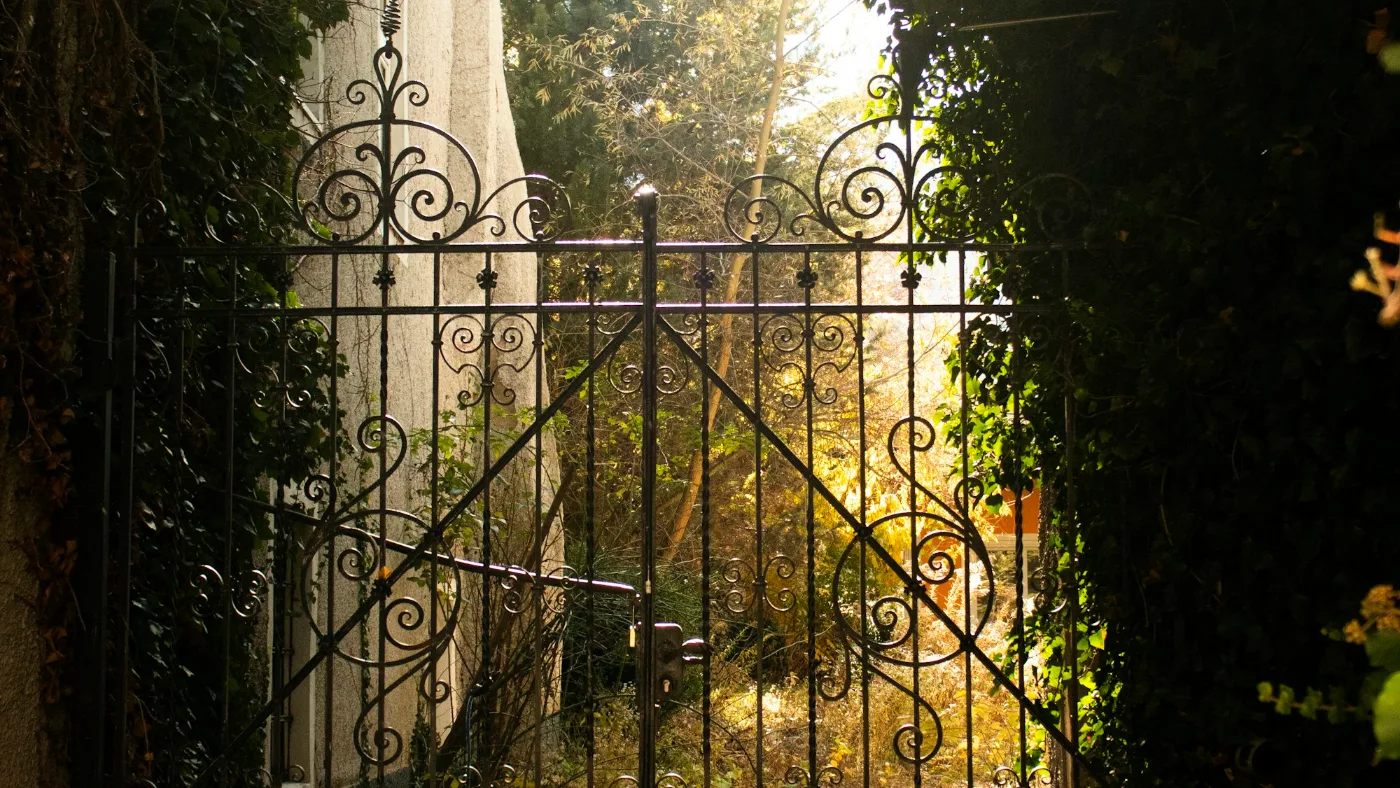 An open gate leading to a garden