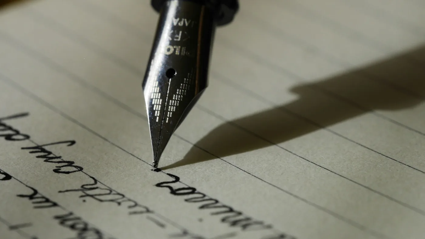 Fountain pen resting on black lined paper