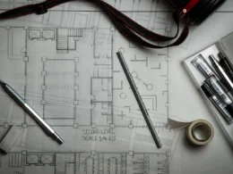 Architectural blueprints with drafting pencils, a metal ruler, and a s