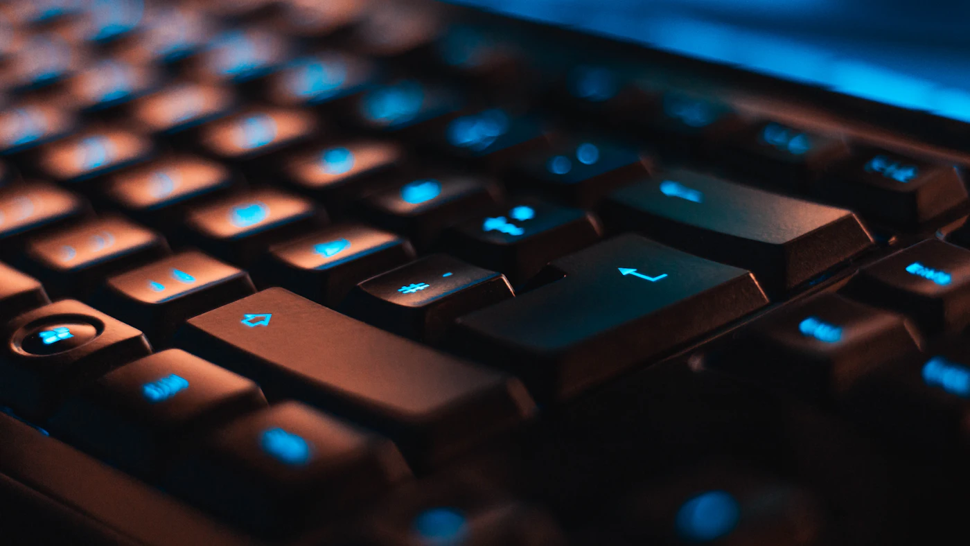 Close-up of dark keyboard keys lit from below in blue