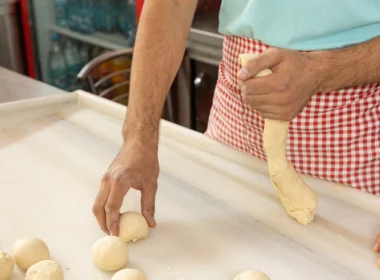 Baker's hands kneading dough in a checked apron