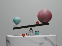 A balance scale with two spheres on a marble pedestal against a grey background