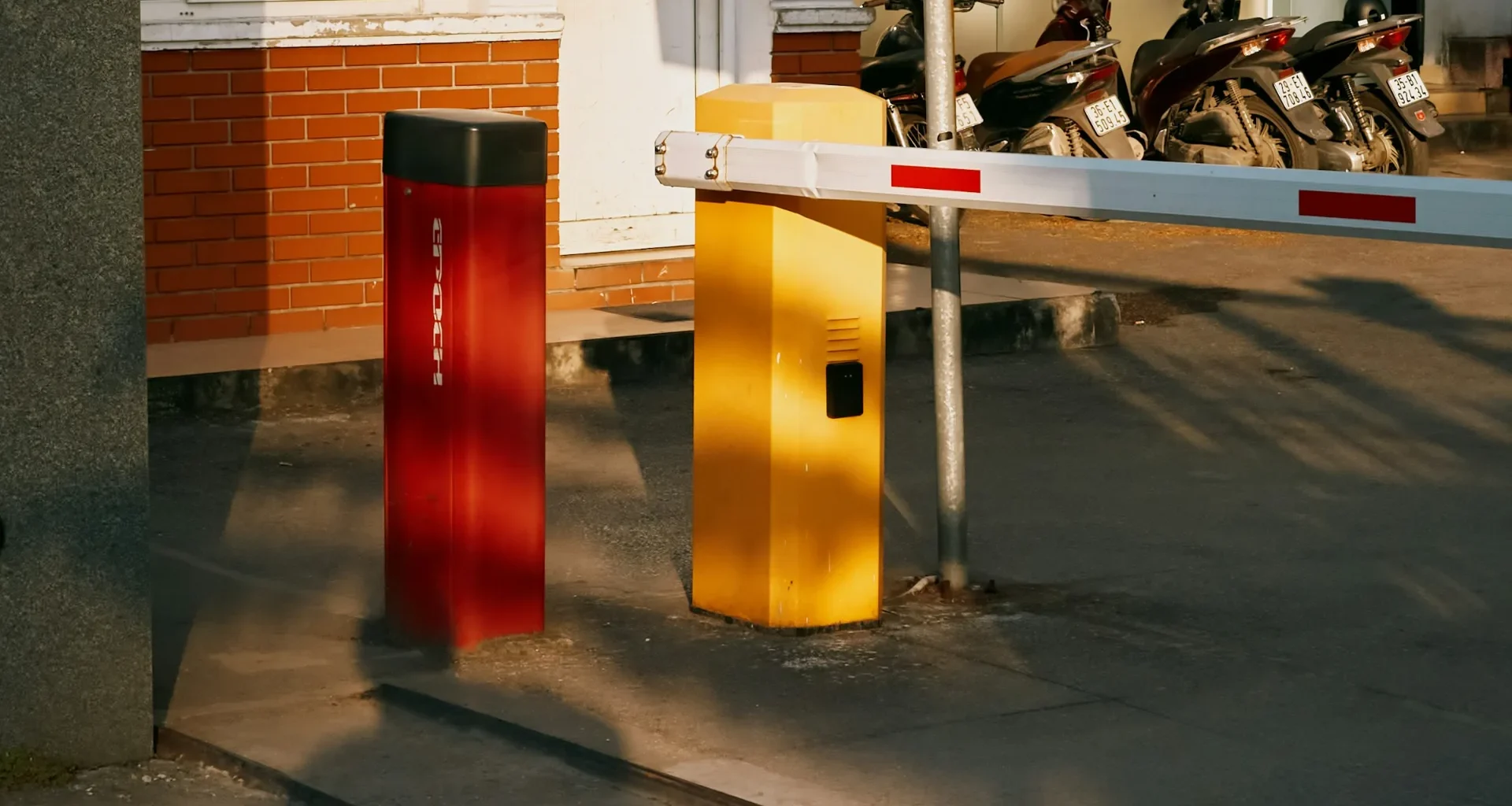 A barrier gate with red and yellow bollards across a vehicle entrance