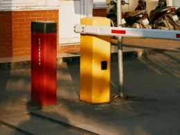 A barrier gate with red and yellow bollards across a vehicle entrance