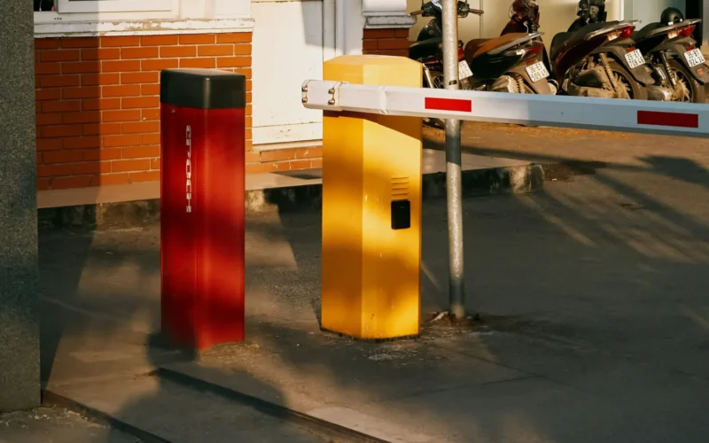 A barrier gate with red and yellow bollards across a vehicle entrance