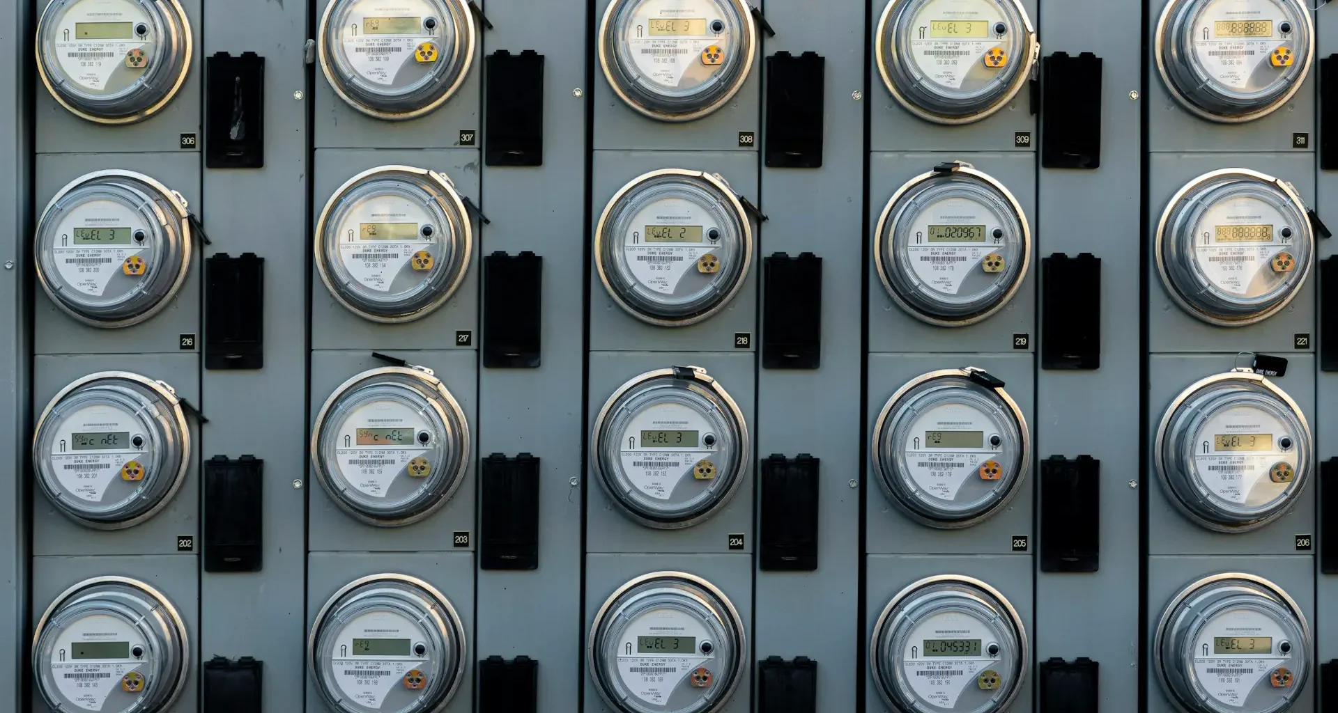 A black and white photograph of an electric utility meter on a wall