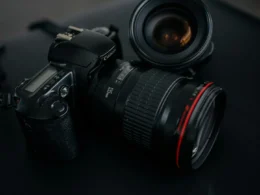 A black DSLR camera resting beside a camera lens