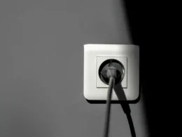 A black electric plug beside a white wall socket
