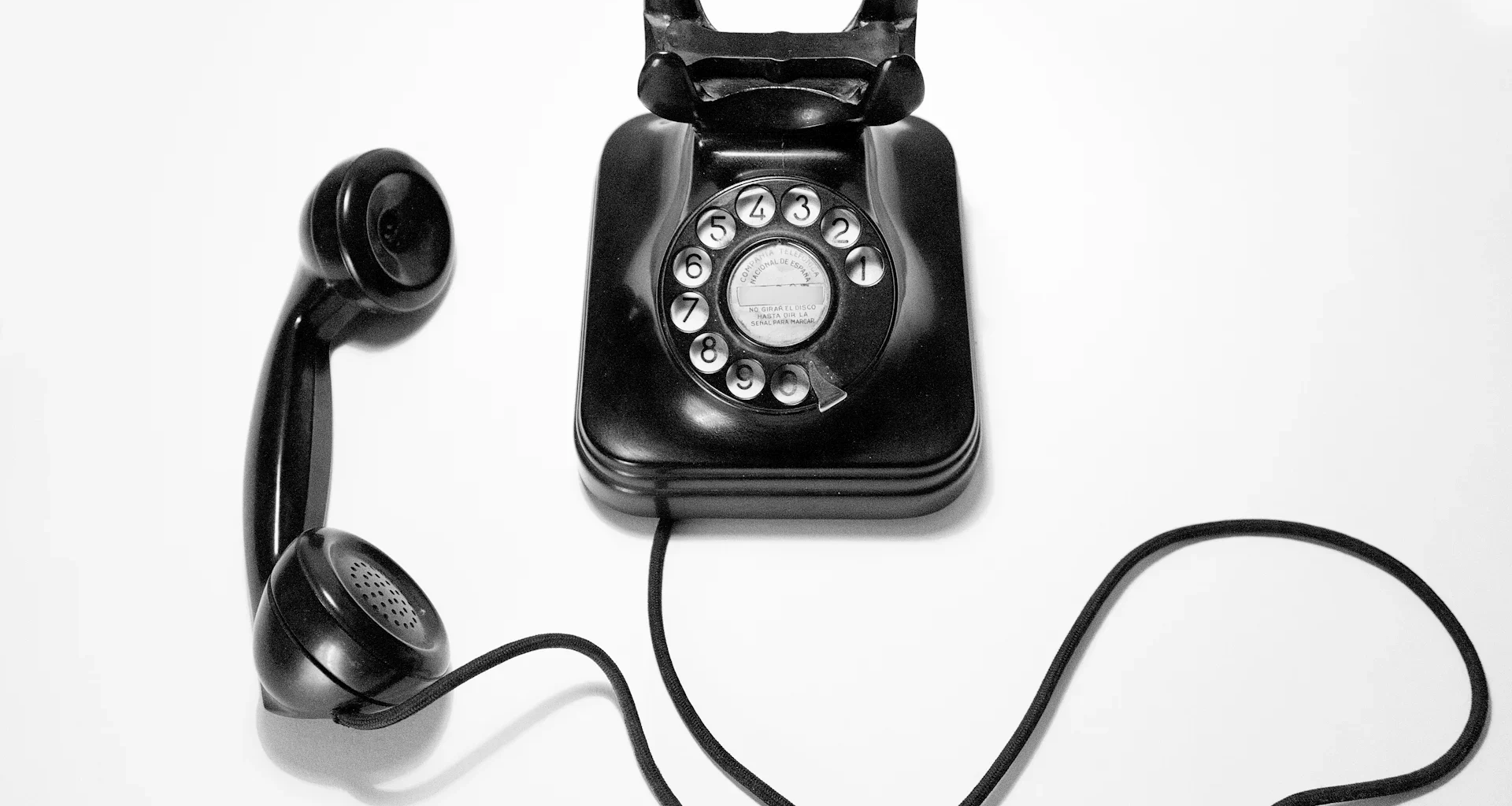 Black rotary dial phone on white surface