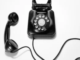 Black rotary dial phone on white surface.