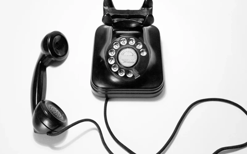 Black rotary dial phone on white surface
