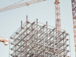 Gray metal building frame beside a tower crane during the day