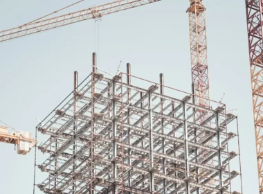 Gray metal building frame beside a tower crane during the day