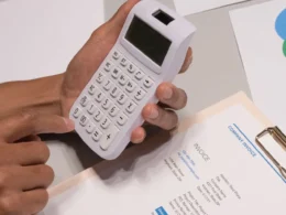 Hands using a calculator beside an invoice, checking Claude Sonnet 5.5 pricing against a monthly AI bill