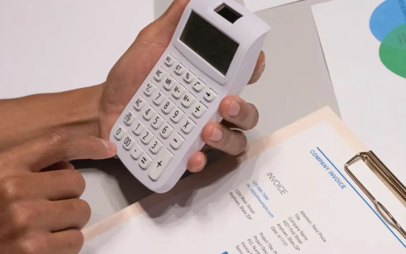 Hands using a calculator beside an invoice, checking Claude Sonnet 5.5 pricing against a monthly AI bill
