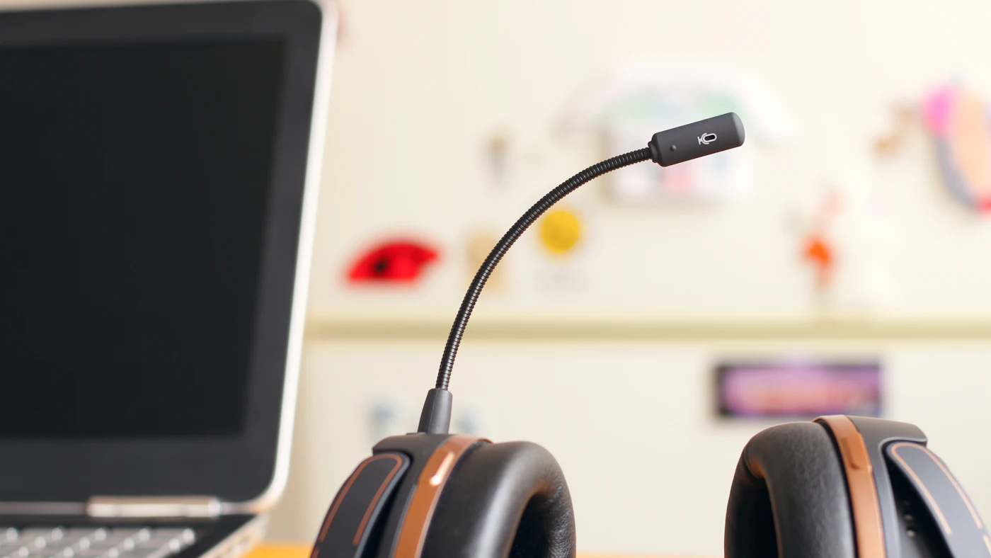 Headset with boom microphone resting beside an open laptop at a support desk