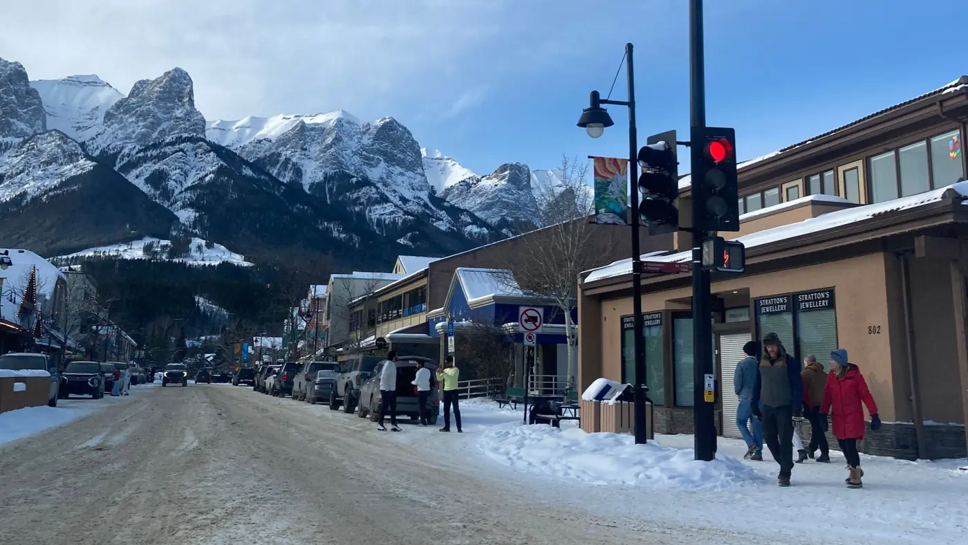 Snowy main street in Canmore, Alberta, with shops, pedestrians and mountains behind, the kind of town a local chamber serves