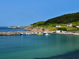 Small harbour with fishing boats below green hills on the Cape Breton Island coast in Nova Scotia