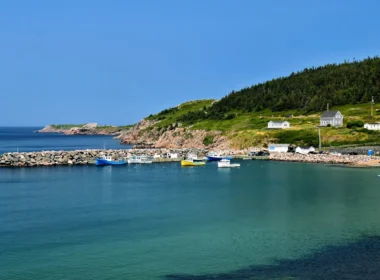 Small harbour with fishing boats below green hills on the Cape Breton Island coast in Nova Scotia