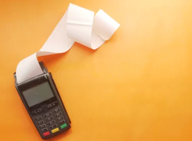 Card payment terminal printing a long paper receipt on an orange surface
