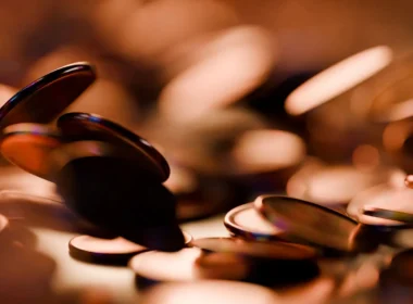 Copper coins scattered in warm low light, a stand-in for the Chamber AI Adoption Program grant split many ways