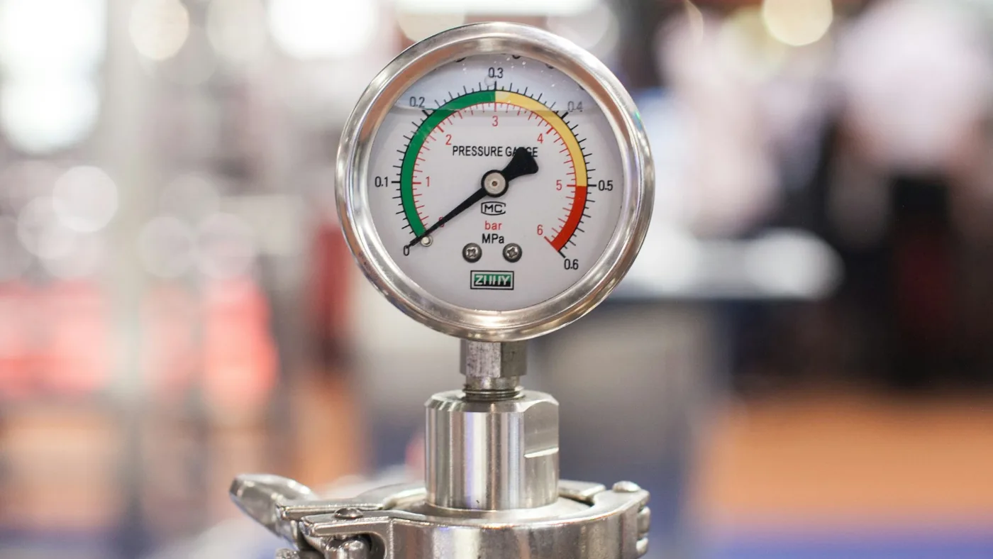 Close-up of a round analog gauge in shallow focus.